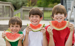 photo of three boys eating watermelon