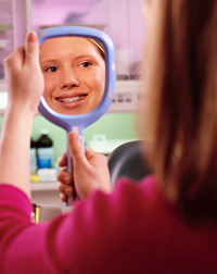 photo of girl with braces looking into a mirror